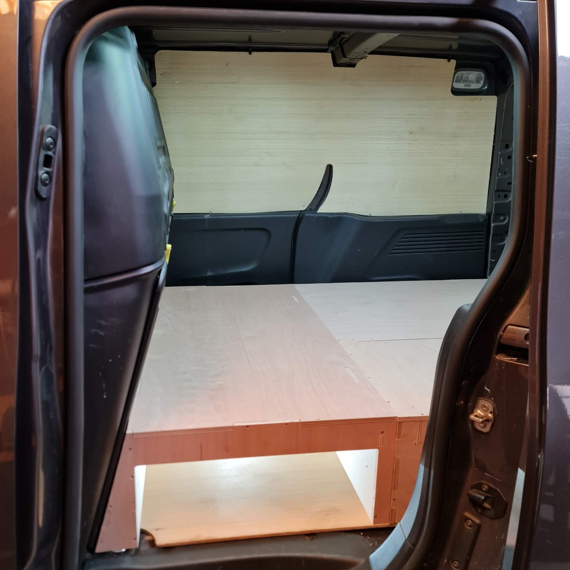 Open car door revealing a wooden interior setup inside a vehicle