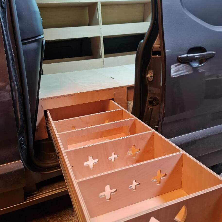 Wooden drawer with cut-out patterns attached to a vehicle door
