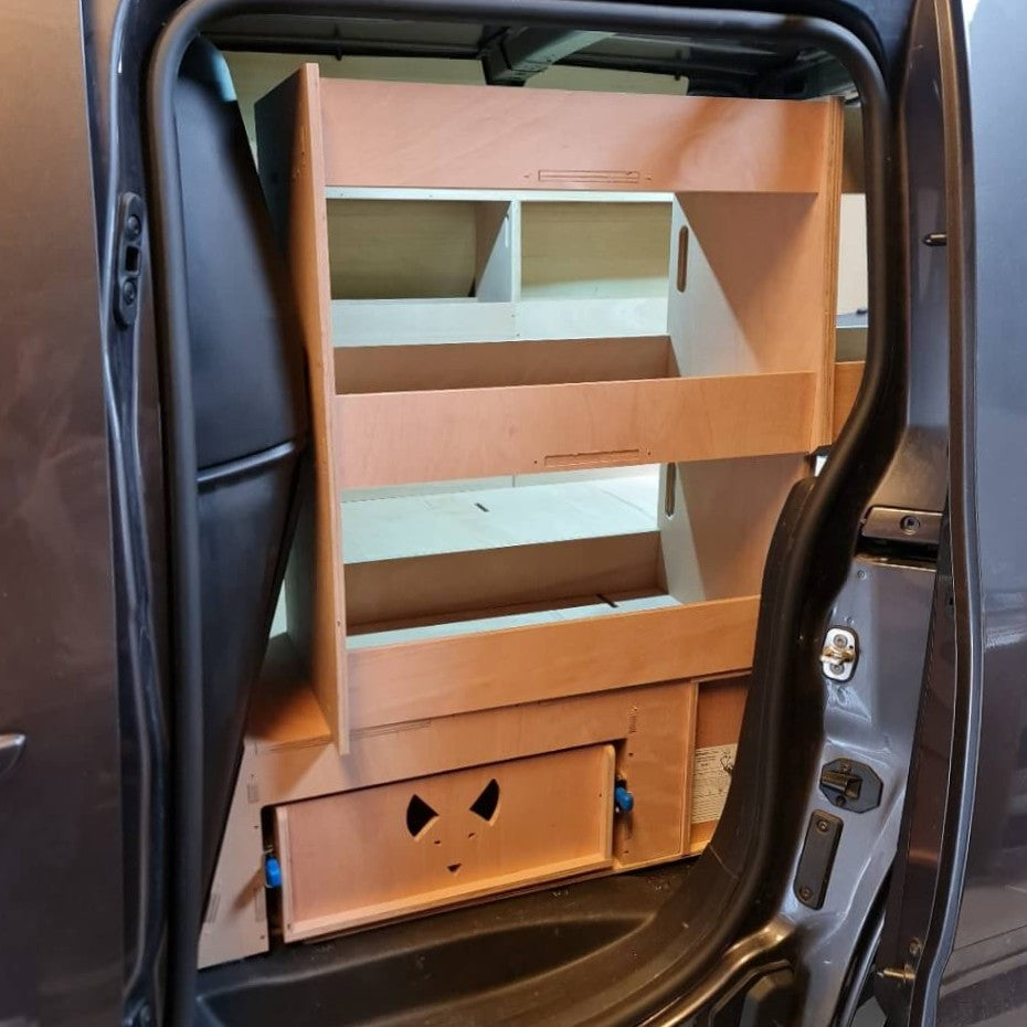 Wooden storage unit with shelves and drawers inside a vehicle.