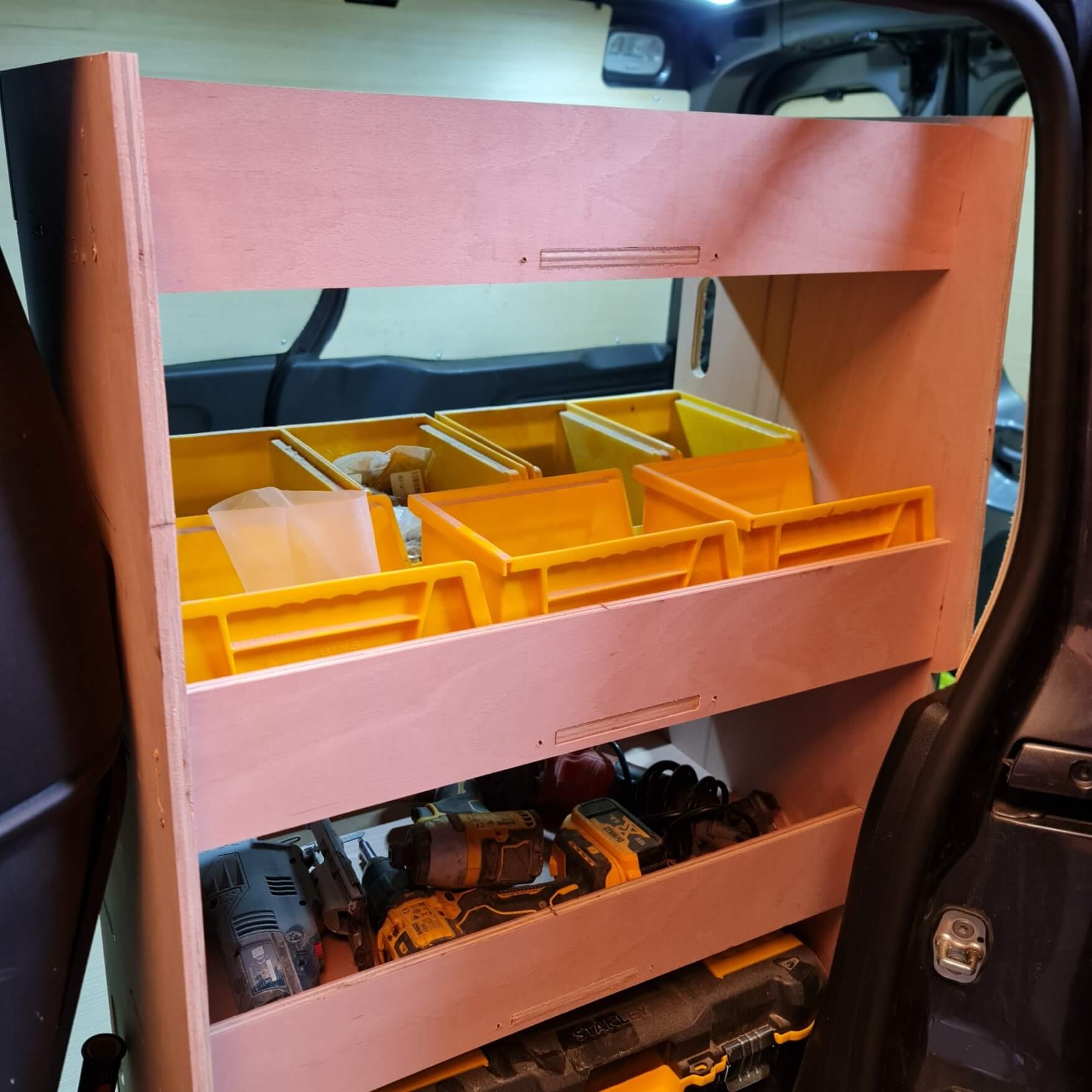 Tool organizer with pink frame and yellow trays containing tools.