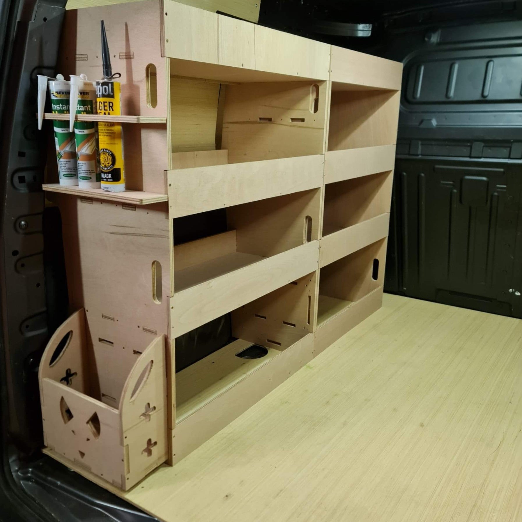 Wooden storage unit with shelves and compartments in a vehicle's cargo area.