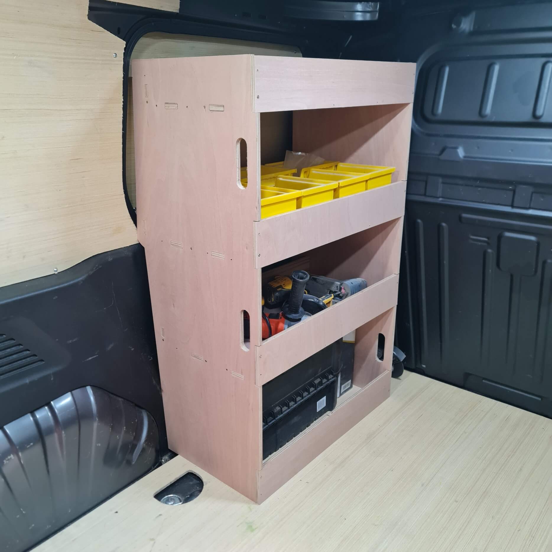 Wooden storage shelf with tools in a vehicle's cargo area