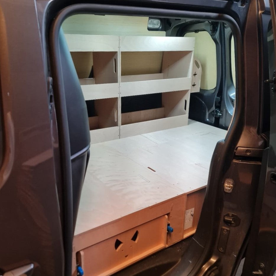 Van interior with a bed setup and storage shelves.