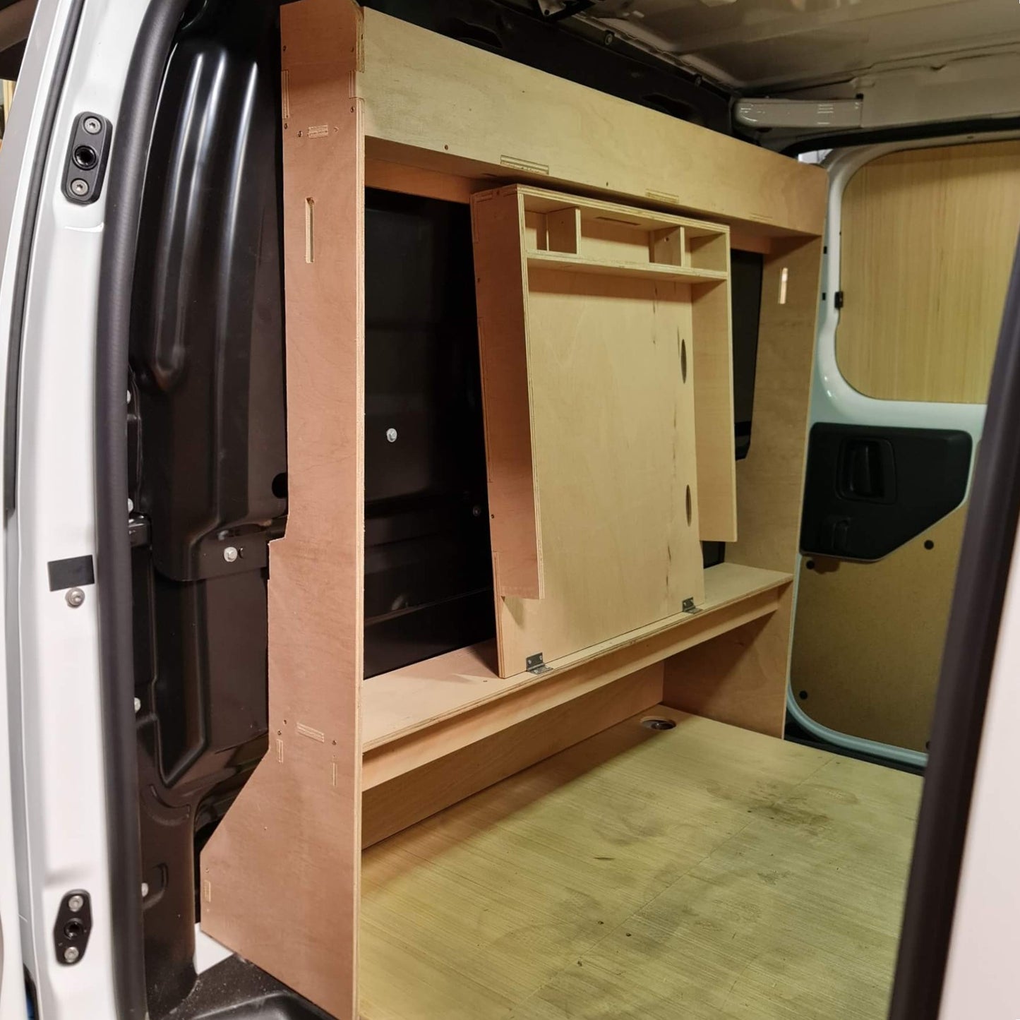 Wooden interior setup inside a vehicle with shelves and a desk.