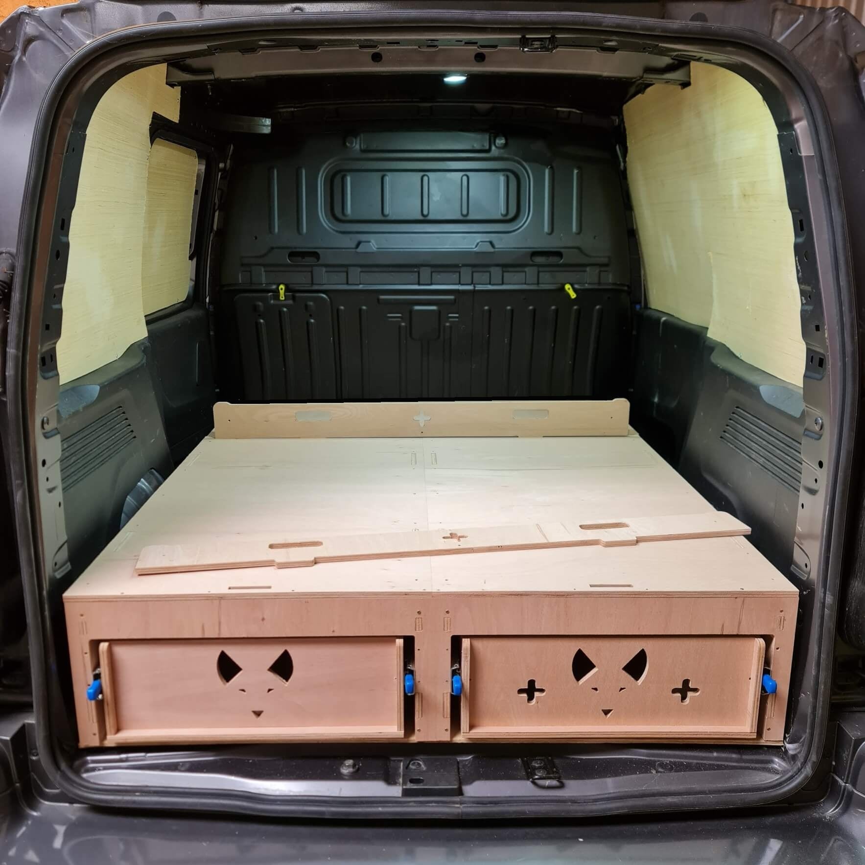 Wooden bed frame with storage drawers in a van's open cargo area