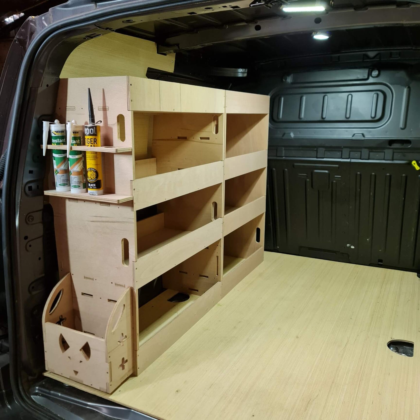 Wooden shelves and storage boxes inside a vehicle's open trunk.