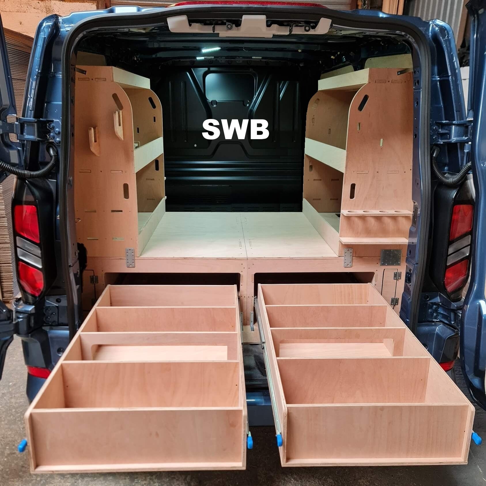 Van interior with wooden storage compartments labeled 'SWB'.