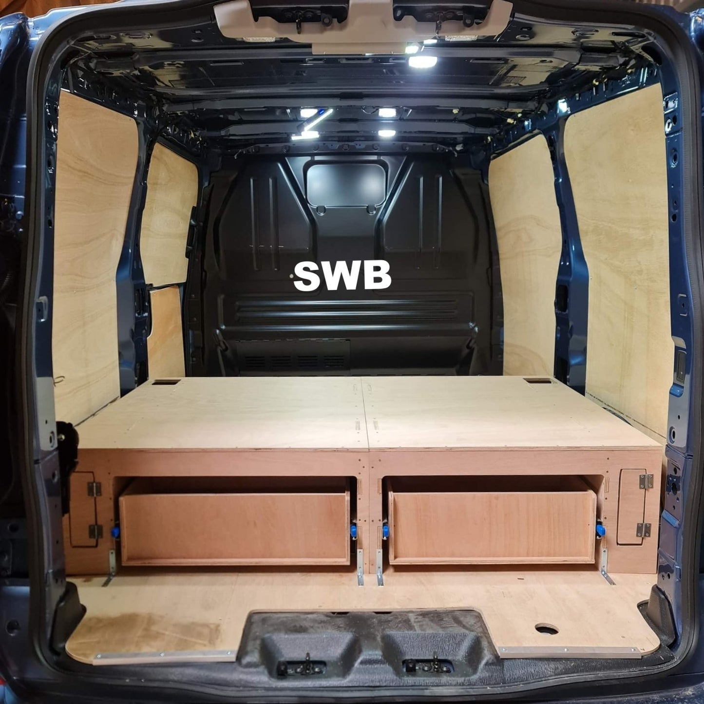 Van interior with wooden floor and storage compartments, labeled 'SWB'.