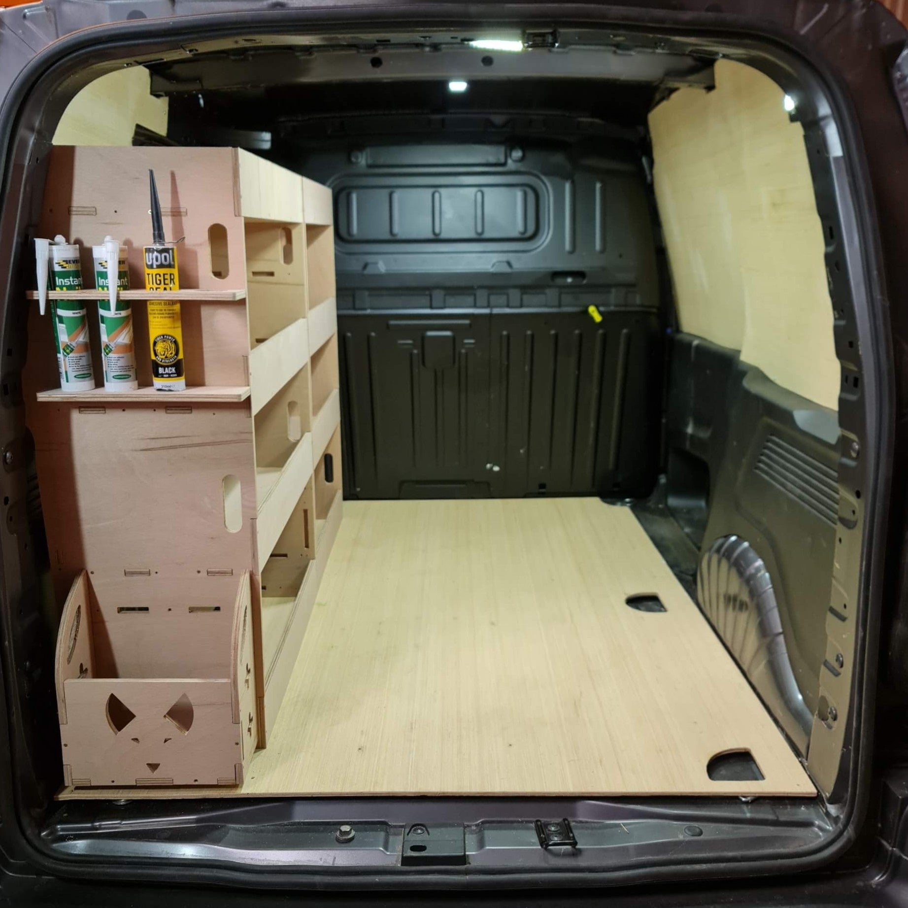 Van interior with wooden shelves and storage compartments.
