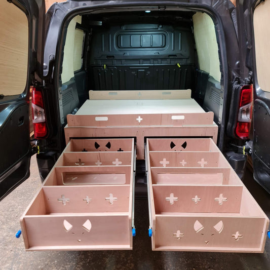 Wooden storage drawers with cut-out designs in the back of a van.