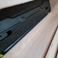 Close-up of a black plastic component on a wooden surface