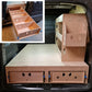 Wooden storage unit with drawers and shelves in a vehicle trunk