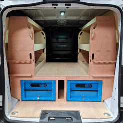 Van interior with wooden walls and blue storage drawers.