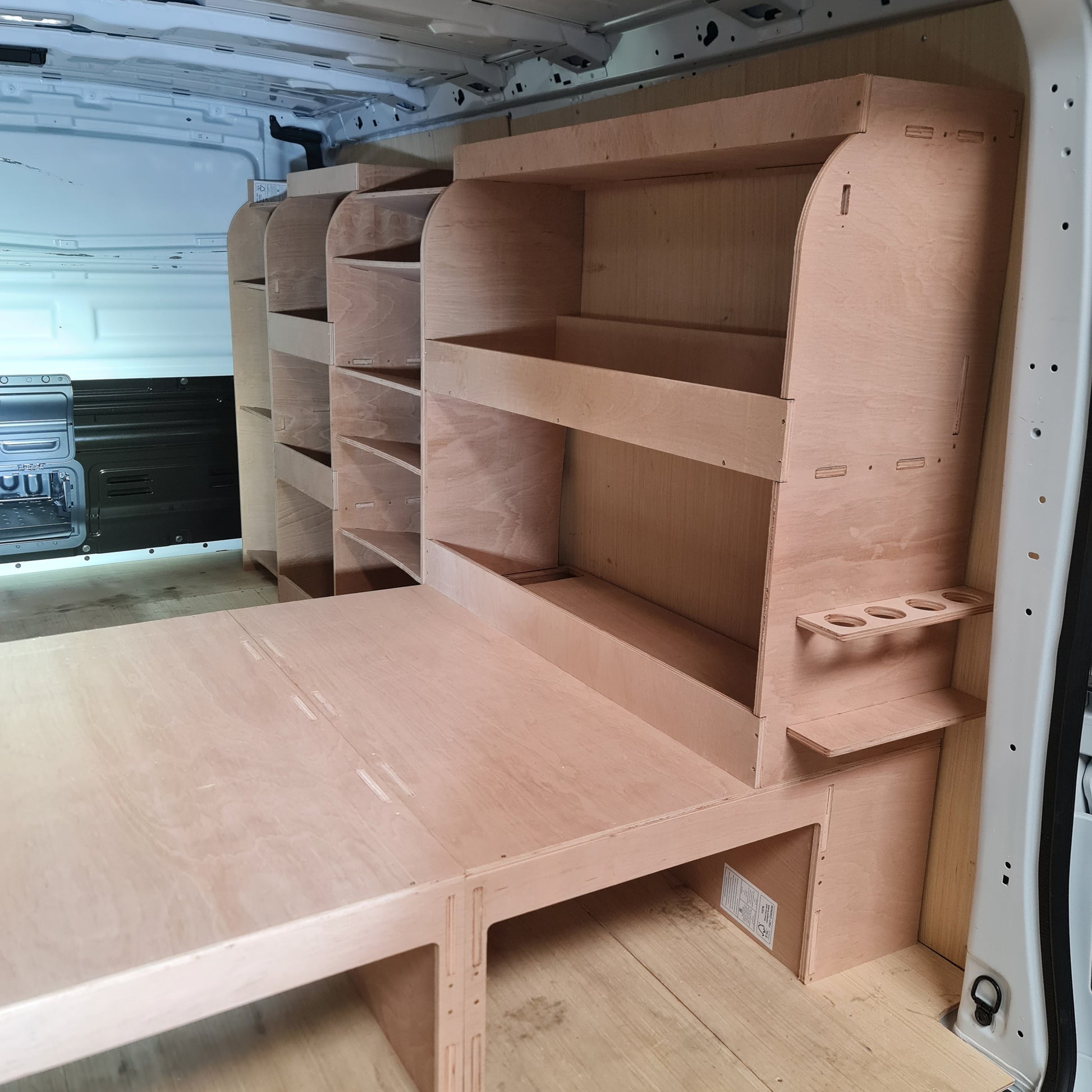 A set of plywood raised floors and racking system installed inside the cargo area of a Peugeot Expert LWB van, featuring various shelves and storage compartments.