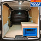 Van interior with a bed setup and a blue vault safe, branded 'VOULT Systems'.
