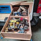 Wooden tool organizer with power tools and car parts inside a vehicle.