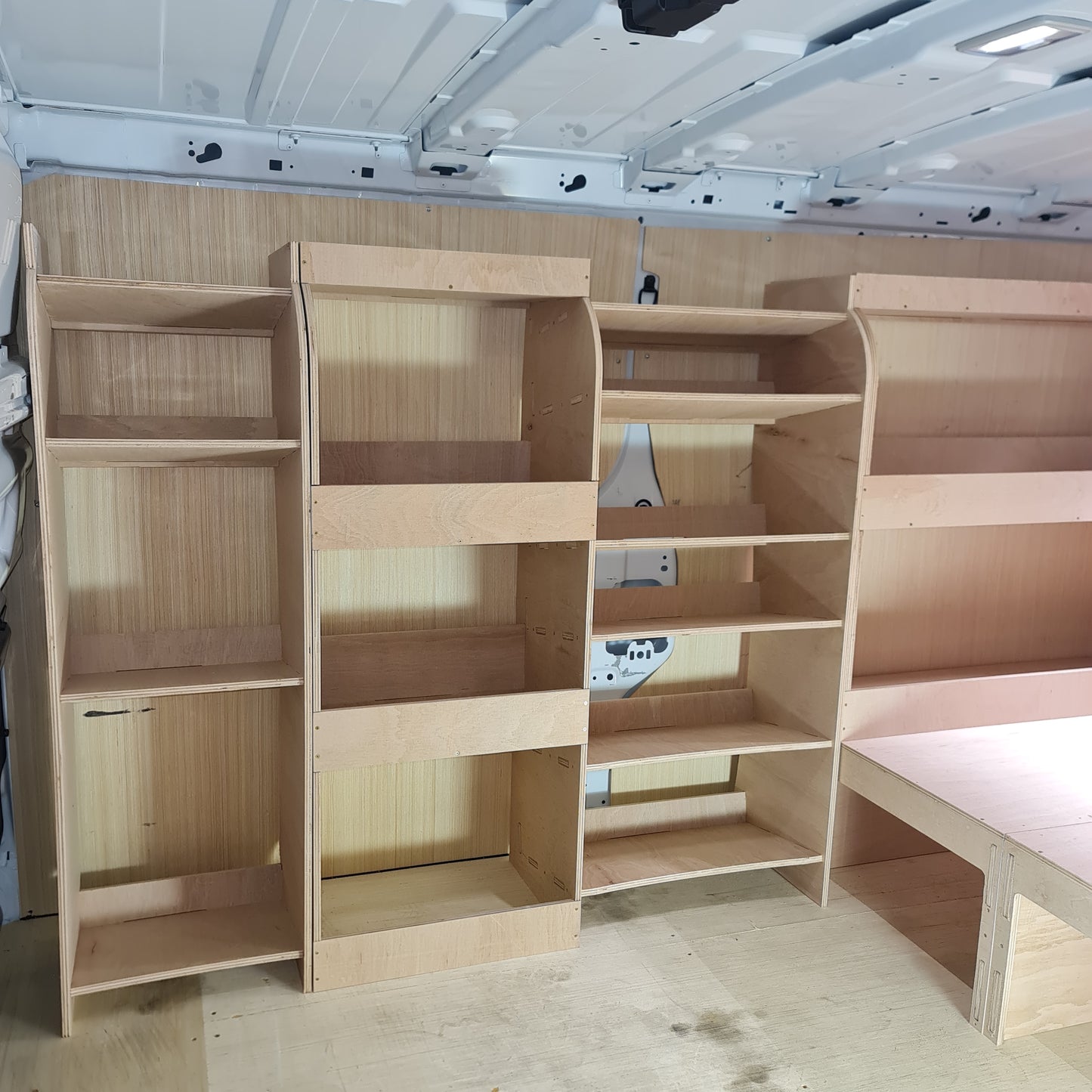 Complete installed van setup with full racking system and raised floor creating organised mobile workshop space.